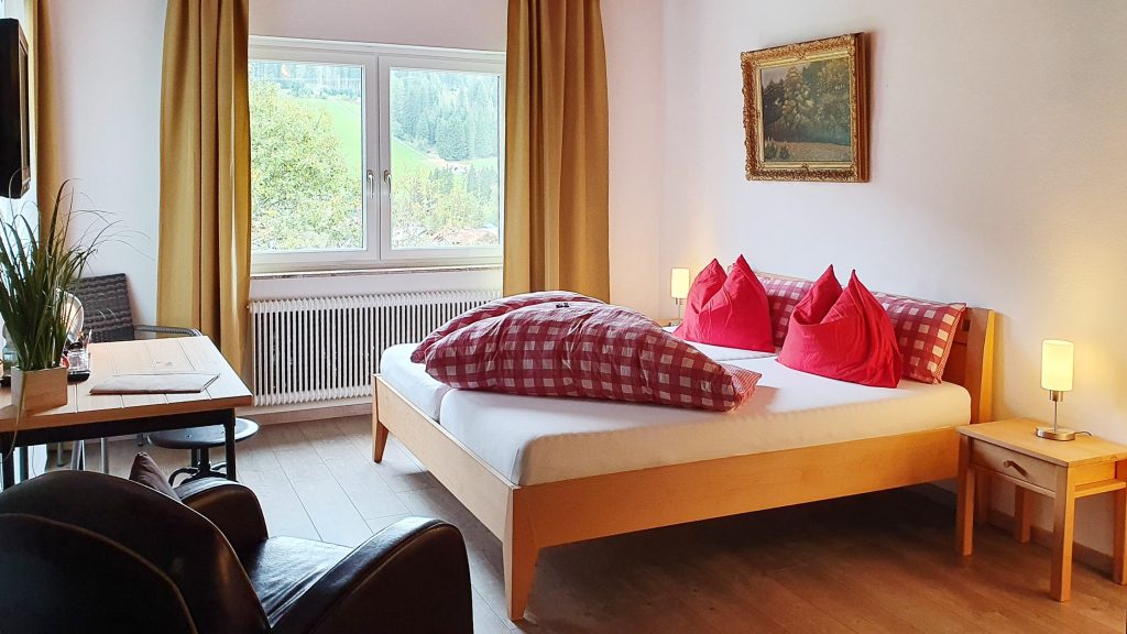 cozy double room with mountain view and red checkered bedding at Boutique Hotel Alpenhof St. Martin am Tennengebirge