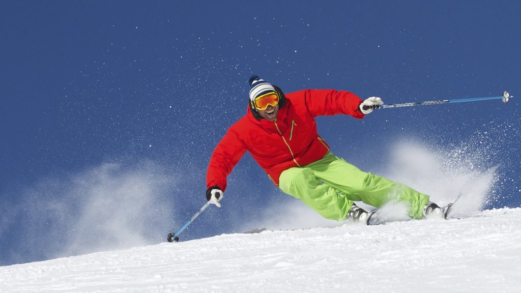 skier carving down a snowy slope under clear blue sky near Boutique Hotel Alpenhof St. Martin am Tennengebirge