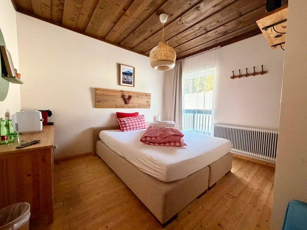 Room 1 at Hotel Alpenhof with a bed, wooden ceiling and balcony door